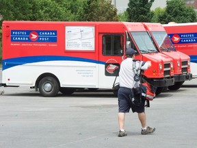 A postal worker walks past Canada Post trucks at a sorting centre in Montreal, Friday, July 8, 2016. The Canadian Union of Postal workers has called for a 30-day truce to negotiate a new contract and avoid a strike or lockout. THE CANADIAN PRESS/Ryan Remiorz