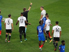 Referee Nicola Rizzoli gives Germany's Bastian Schweinsteiger (top right) a yellow card after he conceded a penalty for hand ball during the Euro 2016 semifinal match against France in Marseille, France, on Thursday, July 7, 2016. (Michael Sohn/AP Photo)