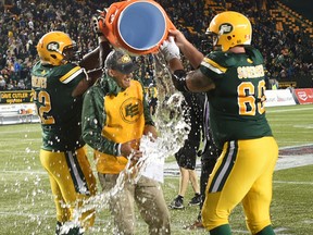 Edmonton Eskimos Chris Greaves, left, and Justin Sorensen douse Jason Maas with water after he posted his first CFL win as a ghead coach Friday, July 8, 2016, at Commonwealth Stadium.