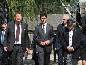 Canadian Prime Minister Justin Trudeau walks through the main gate with Auschwitz survivor Nate Leipciger(right), Foreign Affairs Minister Stephane Dionand the Director of the Auschwitz-Birkenau State Museum Dr. Piotr Cywinski (left) as he begins a tour of the Auschwitz-Birkenau State Museum in Auschwitz, Poland Sunday July 10, 2016. THE CANADIAN PRESS/Adrian Wyld