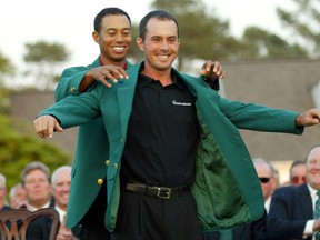 Mike Weir of Canada receives his green jacket from former champion Tiger Woods after Weir defeated Len Mattiace in a one hole playoff to win the 2003 Masters Championship, at the Augusta National Golf Club in Augusta, in this April 13, 2003 file photo. (REUTERS/Shaun Best/Files)