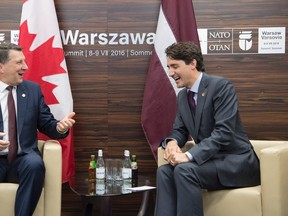Latvian President Raimonds Vejonis(left) jokes about hockey with Canadian Prime Minister Justin Trudeau at the start of a meeting between sessions at the NATO summit in Warsaw, Poland Saturday July 9, 2016. THE CANADIAN PRESS/Adrian Wyld