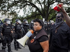 Members of the New Black Panther Party face police in riot gear in front of the Baton Rouge Police Department headquarters as police attempt to clear the protesters from the street in Baton Rouge, La., Saturday, July 9, 2016. (AP Photo/Max Becherer)