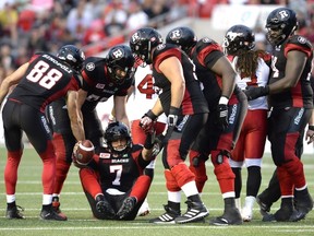 Redblacks QB Trevor Harris gets a hand from teammates after getting sacked by the Stampeders on Friday. The Redblacks next play the Argos on Wednesday.  (CP)