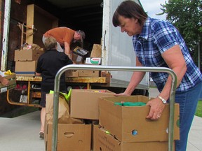 Elaine Patterson, with St. Vincent de Paul, and other volunteers from the Salvation Army and St. Vincent de Paul are at work on Monday July 11, 2016 in Sarnia, Ont. loading food donated during Saturday's Stuff the Bus food drive. More than 9,560 pounds of food was stuffed on two Sarnia Transit buses that collected donations at stops in Sarnia, Bright's Grove and Corunna.  (Paul Morden/Sarnia Observer/Postmedia Network)