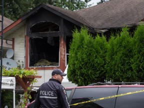 A police officer stands outside a home where a woman was injured in a house fire Sunday and later died, during an investigation in Port Moody, B.C., on Monday July 11, 2016. A woman has died and a man police believe to be her husband has been arrested after a house fire in suburban Vancouver that is being investigated as a homicide. THE CANADIAN PRESS/Darryl Dyck