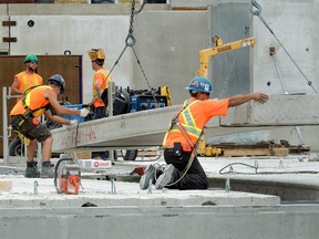 Construction crews guide a concrete floor section into place on Medallion Developments? new apartment building on King and Lyle streets in London Monday.  (MORRIS LAMONT, The London Free Press)
