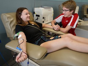 Alyssa Latif, 18, is kept company by John Bouma, 17, as she gives blood for the first time at the Canadian Blood Services clinic in London Monday. (MORRIS LAMONT, The London Free Press)