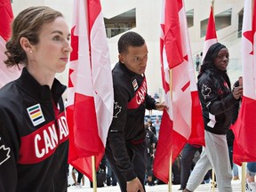 From left, Nicole Sifuentes, Andre De Grasse and Christabel Nettey walk through Canada flags after Canadian Olympic Committee and Athletics Canada announced the athletes nominated to compete at the Rio 2016 Olympic Games, in Edmonton, Alta., on Monday July 11, 2016. THE CANADIAN PRESS/Jason Franson