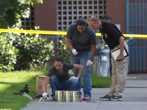 San Diego's Metro Arson Strike Team and SDPD homicide team gather evidence from the sidewalk and grassy area where a homeless person was attacked in downtown San Diego. (John Gibbins/U-T San Diego via AP, File)