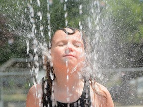 Six-year-old Alyvia Spearing cools off by planting her face in front of a sprinkler. (EDDIE CHAU Simcoe Reformer)