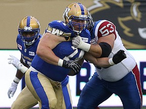 Winnipeg Blue Bombers DL Keith Shologan (left) is held by Montreal Alouettes OL Philippe Gagnon during CFL action last month. (Kevin King/Winnipeg Sun file photo)
