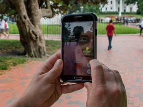 A woman holds up her cellphone as she plays the "Pokemon Go" game in Lafayette Park in front of the White House in Washington, DC, July 12, 2016. (JIM WATSON/AFP/Getty Images)