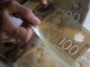 Canadian $100 bills are counted in Toronto in this Feb. 2, 2016 file photo. A report by HSBC suggests that nearly half of working-age Canadians are not saving for retirement. (THE CANADIAN PRESS/Graeme Roy)