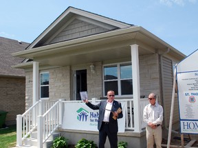Habitat for Humanity – Heartland Ontario CEO Jeff Duncan, left, speaks in front of the first-ever Habitat home in St. Thomas at a dedication ceremony  in 2014. The home made it to completion despite a series of obstacles. Standing with Duncan is Habitat past chairman Phil Squire.
