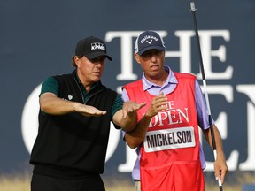 Phil Mickelson (left) talks to his caddie, Jim McKay, on the 18th green as they look at his putt during the first round of the British Open at the Royal Troon Golf Club in Troon, Scotland, Thursday, July 14, 2016. (AP Photo/Matt Dunham)
