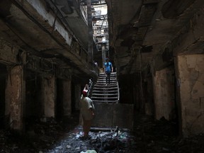 People inspect a burned mall after the last week massive suicide truck bomb attack that killed at least 186 people and was claimed by the Islamic State group, in the Karada neighborhood of Baghdad, Iraq, Monday, July 11, 2016. (AP Photo/Hadi Mizban)