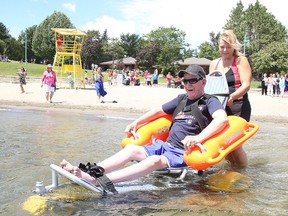 Lionel Courtemanche tries out the new Mobi-chair at the main beach at Bell Park with the help of Holly Janakowski, a member of the accessibilty advisory panel, on Thursday. The floating wheelchair allows those with disabilities to enjoy the water. (Gino Donato/Sudbury Star)