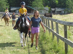 Lead wrangler Jessie Tucker walks along with Georgia Austin, 9, of London riding one of the horses at Forest Cliff Camp on Thursday July 14, 2016, on the grounds of the summer camp in Lambton Shores, Ont. The camp, home to as many as 240 campers each week, has been operating since the 1940s.
Paul Morden/Sarnia Observer/Postmedia Network