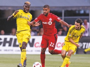 TFC forward Jordan Hamilton splits Crew defenders Tony Tchani (left) and Michael Parkhurst during the second half of Wednesday’s match in Columbus. With Giovinco being rested, Hamilton’s goal let TFC escape with a 1-1 road draw. (AP)
