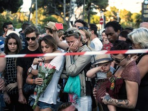 People react as they gather at a makeshift memorial to honor the victims of an attack, near the area where a truck mowed through revelers in Nice, southern France, Friday, July 15, 2016. A large truck mowed through revelers gathered for Bastille Day fireworks in Nice, killing more than 80 people and sending people fleeing into the sea as it bore down for more than a mile along the Riviera city's famed waterfront promenade. (AP Photo/Laurent Cipriani)