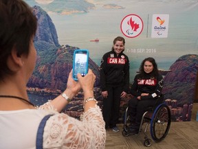 A woman takes a photo of Nydia Langill, left, of Mississauga, Ont., and Tammy Cunnington, of Red Deer, Alta., following an unveiling ceremony for the Canadian Paralympic swim team, in Ottawa on Thursday, July 14, 2016. (THE CANADIAN PRESS/Adrian Wyld)