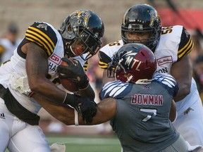 Hamilton Tiger-Cats running back C.J. Gable (left) rumbles past Montreal Alouettes’ John Bowman on July 15. (The Canadian Press)