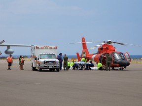 In this photo provided by the U.S. Coast Guard, Coast Guard crews safely deliver David McMahon and Sidney Uemoto to emergency medical personnel in Kona, Hawaii, Friday, July 15, 2016, following their rescue nine miles off Kona. They were both rescued by a Coast Guard MH-65 Dolphin helicopter crew following an expansive joint search by Navy, Royal New Zealand air force, U.S. Air Force and Coast Guard crews. They reportedly sustained only minor injuries in the crash. (Kevin Cooper/U.S. Coast Guard via AP)