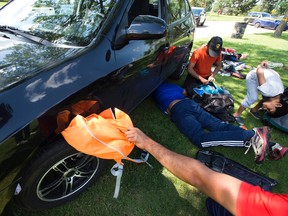 Cricket players retrieve their belongings from under a car after it jumped a curb and landed on five-year-old Smith Lee Alphons at Coronation Park on Saturday, July 16, 2016. Smith was pulled to safety and taken to hospital with non life-threatening injuries.