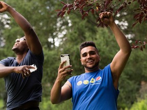 Simrit Birdi and Josh Konu play Pokemon Go on their cellphones at the Alberta Legislature grounds.