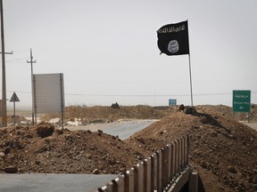 A flag of the Islamic State (IS) is seen on the other side of a bridge at the frontline of fighting between Kurdish Peshmerga fighters and Islamist militants in Rashad, on the road between Kirkuk and Tikrit, on September 11, 2014. (JM LOPEZ/AFP/Getty Images)
