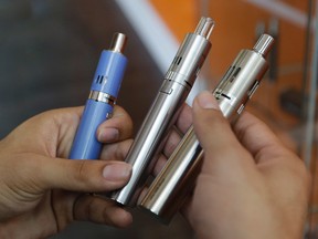 In this July 7, 2015 file photo Vapor Spot employee Angel Delao displays a variety of e-cigarettes for sale at the store, in Sacramento, Calif.   (AP Photo/Rich Pedroncelli, file)
