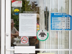 Brian Knechtel, owner and president of Knechtel Food Market, is pictured in reflection talking to a customer about his store’s closure, which was announced on Facebook and in the noticed seen here taped to the grocery store’s front doors. (Darryl Coote/Reporter)