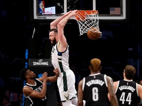 Milwaukee Bucks' Miles Plumlee, top, hits a reverse dunk in front of Brooklyn Nets' Thaddeus Young. (AP Photo/Seth Wenig, File)