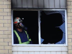 Framed by a broken window, a fire investigator on Monday looks through an apartment damaged in Saturday's fatal fire in Amherstview. (Elliot Ferguson/The Whig-Standard)