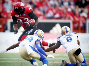 Calgary Stampeders Jerome Messam avoids a tackle by Julian Posey and Chris Randle of the Winnipeg Blue Bombers in CFL football in Calgary, Alta., on Friday, July 1, 2016.