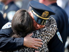 Mourners hug after the burial of Jefferson Parish Sheriff's Detective David Michel Jr., in Westwego, La., Monday, June 27, 2016. The 50-year-old Michel was shot three times during a pedestrian stop June 22 in Harvey. Nineteen-year-old Jerman Neveaux, of New Orleans, was arrested on charges of first-degree murder, resisting an officer, battery of a police officer and aggravated assault with a firearm. (AP Photo/Gerald Herbert)