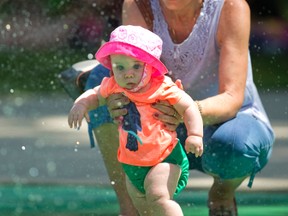 Theresa Barritt of Halifax and her London granddaughter, Madeline Doyle, eight months, beat the heat Monday at the Gibbons Park splash pad. There’s more heat and humidity heading London’s way. (MORRIS LAMONT, The London Free Press)