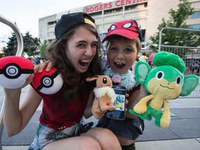 Kali Hacking-Pace (L) and J.J. Hacking play Pokemon Go at the base of the CN Tower  on Monday July 18, 2016. (Craig Robertson/Toronto Sun)
