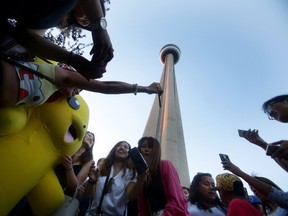 Fans swarm a person in costume as a Pikachu under the CN Tower at the start of the Pokemon Go release party in Toronto on Monday, July 18, 2016. Sunday marked the official release of the game in Canada. THE CANADIAN PRESS/Cole Burston