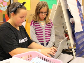 Grade 8 student Emily Power helps fellow student Isabelle Jensen navigate a laptop at a summer learning camp session held at St. Matthew Catholic School Tuesday. More than 80 Sarnia-Lambton elementary students are currently participating in the three-week-long summer camp hosted by the St. Clair Catholic District School Board. (Barbara Simpson/Sarnia Observer/Postmedia Network)