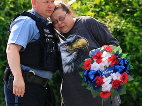 Kansas City, Kan., police officer Brad Lightfoot, left, consuls Susan Goble at the shooting scene of a police officer in Kansas City, Kan., Tuesday, July 19, 2016. Goble knows the family of the fallen officer and hoped to place a wreath near the site of the shooting. (AP Photo/Orlin Wagner)