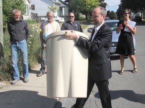 Kingston Mayor Bryan Paterson delivers the city's 10,000th rain barrel to the home of Alicia Peltsch-Williams and her husband Scott Williams on Tuesday. The program has been underway since 2006. (Michael Lea/The Whig-Standard)