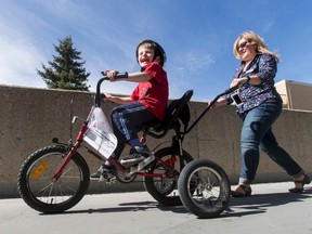 Jeremiah Botbijl, 6, is thrilled atop a customized bicycle while being followed by Sheralee Stelter, executive director of Cerebral Palsy Kids and Families, at the group’s headquarters in Calgary on Saturday, April 2. About 35 kids with physical disabilities like cerebral palsy, down syndrome and autism were fitted with customized bicycles; the group expects to give out 200 bikes this year but could do more if supplies were available. Lyle Aspinall, Postmedia Network.
