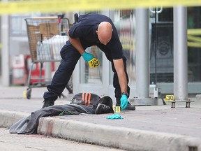 A Winnipeg police forensics officer places evidence markers near blood stained clothing following a homicide in front of MTS Centre earlier this month. (Brian Donogh/Winnipeg Sun file photo)