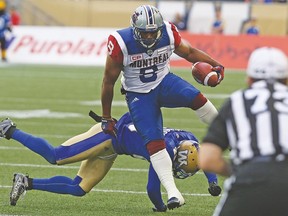 Alouettes slotback Nik Lewis leaps through an attempted tackle by the Blue Bombers. (Kevin King, Postmedia)