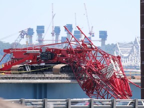 A crane used in the construction of the new bridge spanning the Hudson River alongside the Tappan Zee Bridge, lays on and over the edge of the new roadway after it collapsed Tuesday, across the span of the old bridge as seen from Nyack, N.Y., Wednesday, July 20, 2016. Most of the lanes of the bridge north of New York City have reopened after a crane collapsed across the entire width of the bridge, but transportation officials are still advising motorists to plan for extra delays. State and federal officials are investigating what caused a huge construction crane to collapse across the busy bridge. (AP Photo/Seth Wenig)