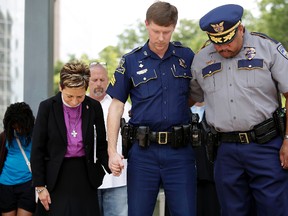 Louisiana State Police Officer Jared Sandifer, centre, and Baton Rouge Police Lieutenant Terrance Watkins, right, pray during a vigil for Baton Rouge Police Officers Montrell Jackson, Matthew Gerald and East Baton Rouge Parish Sheriff Deputy Brad Garafola in Baton Rouge on Thursday. A Manitoba man received a tongue-lashing in court, including from his own lawyer, for posting comments that cheered on the shootings. (Joshua Lott/Getty Images)