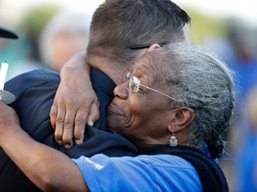 Veda Monday hugs a police officer during a ceremony for fallen Kansas City, Kan. police Capt. Robert Melton in front of City Hall, Wednesday, July 20, 2016, in Kansas City, Kan. A suspect in a drive-by shooting fatally shot Melton on Tuesday as the officer was sitting in his patrol car. (AP Photo/Charlie Riedel)