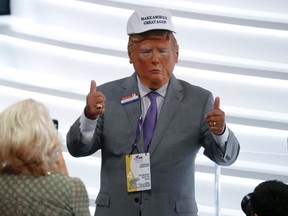 A Georgia delegate wearing a Donald Trump mask poses near the stage at Quicken Loans Arena during the final day of the Republican National Convention in Cleveland, Thursday, July 21, 2016. (AP Photo/Paul Sancya)